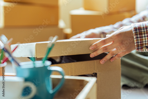 Young man holding open cardboard box with things for moving into new house