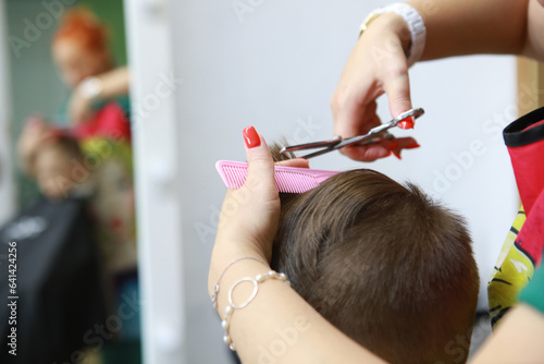 Caucasian boy getting hairstyle in barbershop.Barber shop. Barbershop hairdresser makes hairstyle to a boy.
