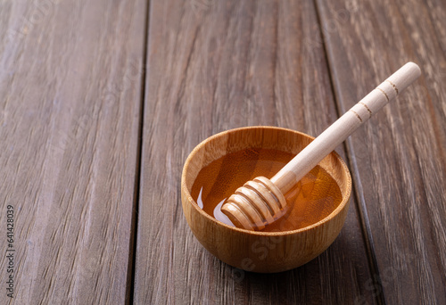 Honey in a tiny bowl with wooden dipper and copy space