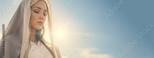 Woman in image Virgin Mary Mother of Jesus Christ in holy light. Portrait of young woman in veil in rays of the sun. Mother of God, Biblical motif.The Assumption of the Blessed Virgin Mary, August 15