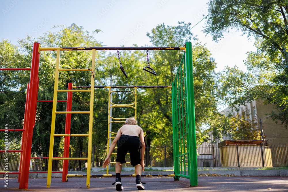 A sports child performed with a jump from the crossbar. Street workout on a horizontal bar in the school park.