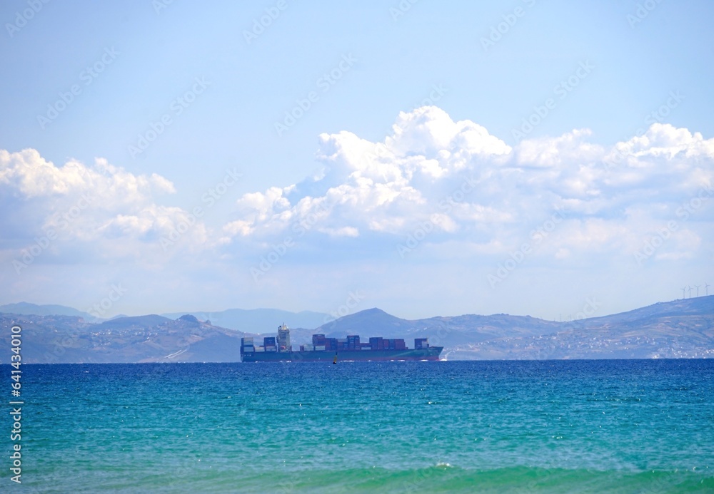 container ship passing through the Strait of Gibraltar and entering the Atlantic Ocean, seen from Andalusia, Morocco behind, Spain