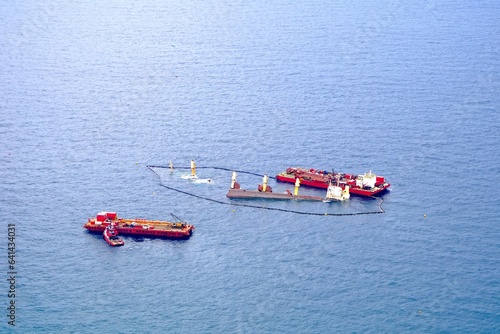 sunk cargo ship after collision with a tanker near Gibraltar, shipwreck, oil boom, environmental pollution, oil spill