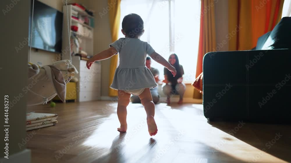 Baby first steps.Child kid runs across floor to family.kid learn to walk and run with help of his parents.Happy family at home first steps of toddler.father encourages baby teaches to take first steps