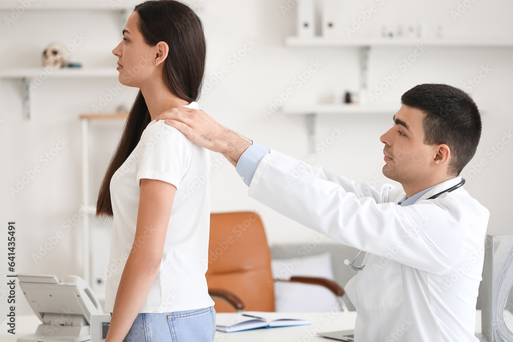 Male doctor checking posture of young woman in clinic Male doctor checking posture of young woman in clinic