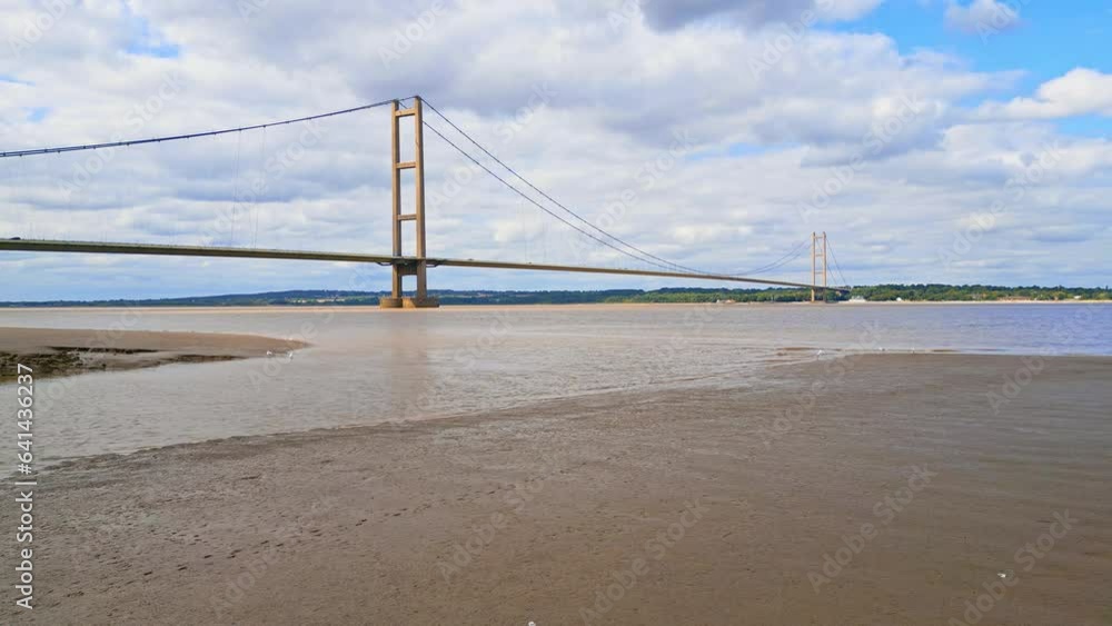 Aerial drone view of Humber Bridge, 12th largest suspension span, gracefully crossing River Humber, connecting Lincolnshire to Humberside with traffic. Aerial drone view of Humber Bridge, 12th largest suspension span, gracefully crossing River Humber, connecting Lincolnshire to Humberside with traffic.