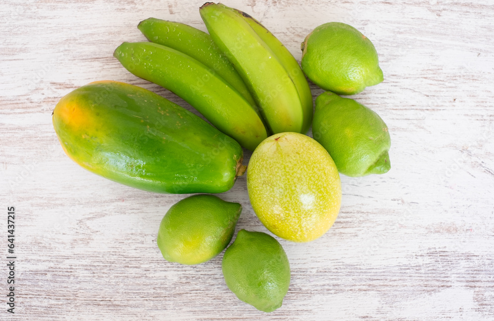 Different fresh green fruits on wooden background, papaya, banana, lime, passion fruit Different fresh green fruits on wooden background, papaya, banana, lime, passion fruit