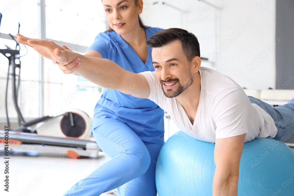 Obraz premium Female physiotherapist working with young man in rehabilitation center