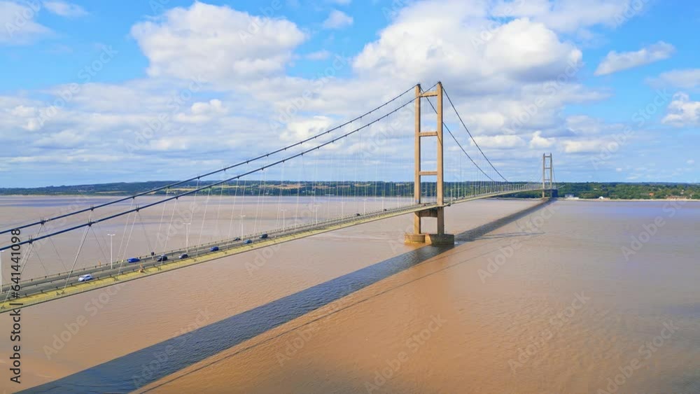 Aerial drone view of Humber Bridge, 12th largest suspension span, gracefully crossing River Humber, connecting Lincolnshire to Humberside with traffic. Aerial drone view of Humber Bridge, 12th largest suspension span, gracefully crossing River Humber, connecting Lincolnshire to Humberside with traffic.