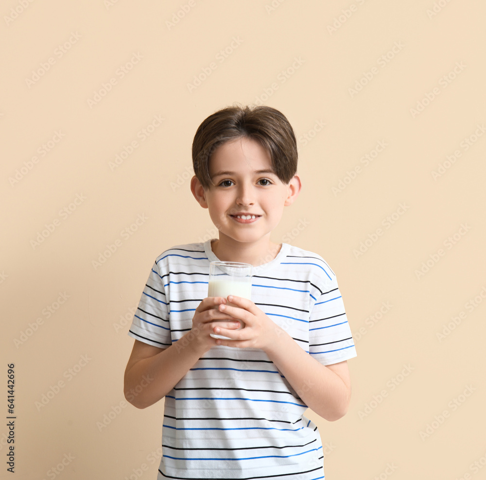 Happy little boy with glass of milk on beige background Happy little boy with glass of milk on beige background