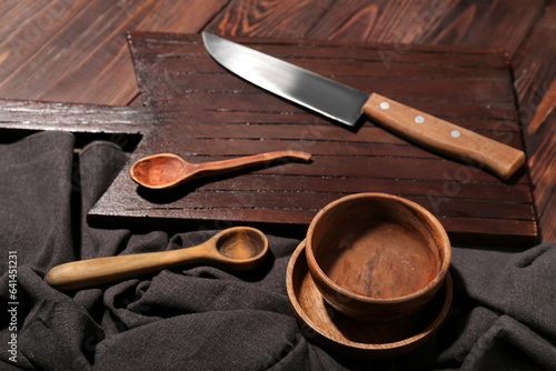 New cutting board, bowls, knife and spoons on wooden background