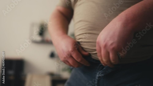 Closeup of man unable to button his jeans, overeating consequences, weight gain photo