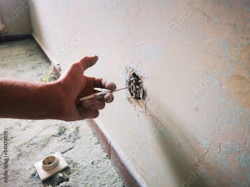 An electrician works unsafely on switches and outlets in a residential electrical system photo