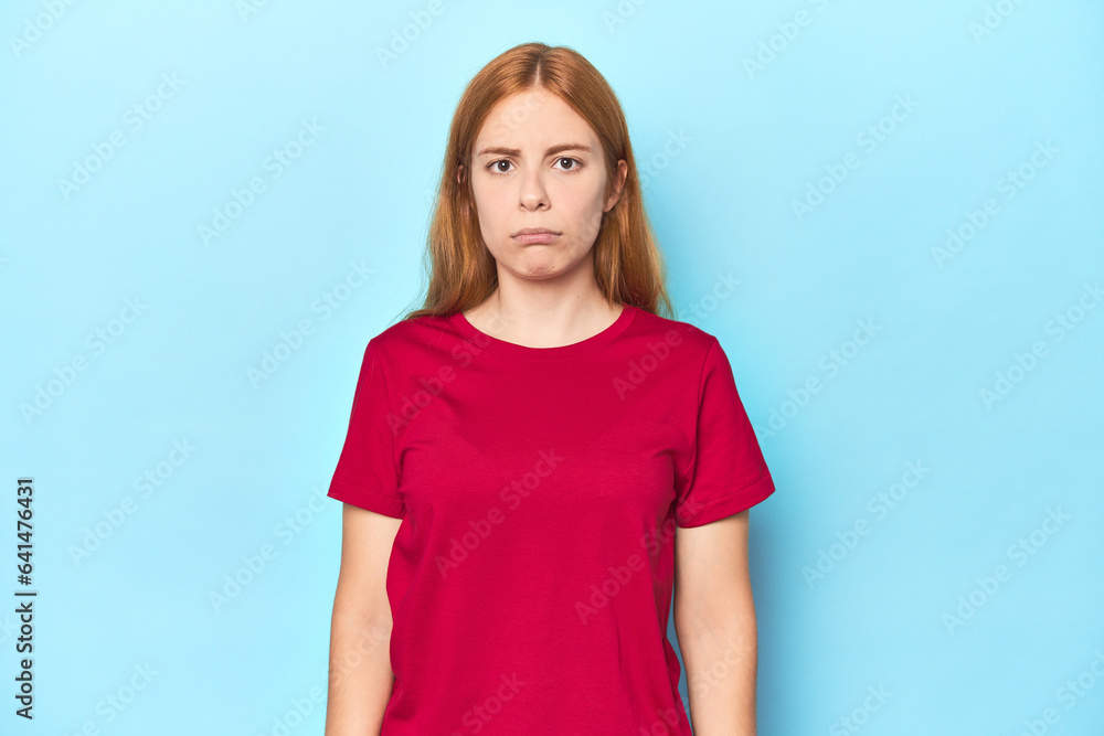 Redhead young woman on blue background sad, serious face, feeling miserable and displeased. Redhead young woman on blue background sad, serious face, feeling miserable and displeased.