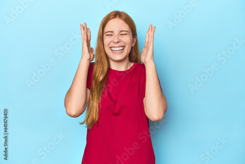 Redhead young woman on blue background joyful laughing a lot. Happiness concept.