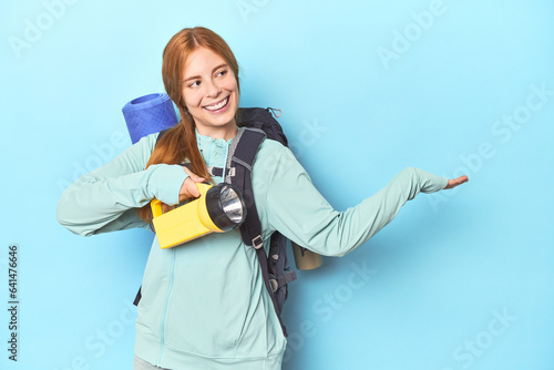 Redhead mountaineer with backpack and flashlight in studio