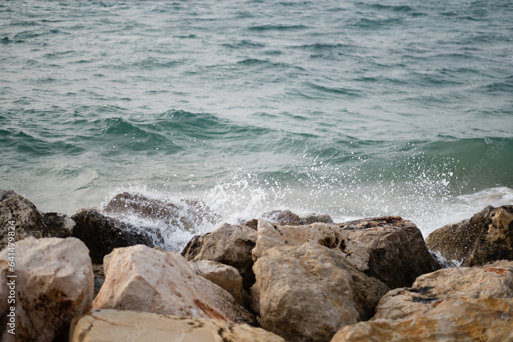 The waves of the Mediterranean Sea crash against boulders along the shoreline of Tel Aviv, near Jaffa.