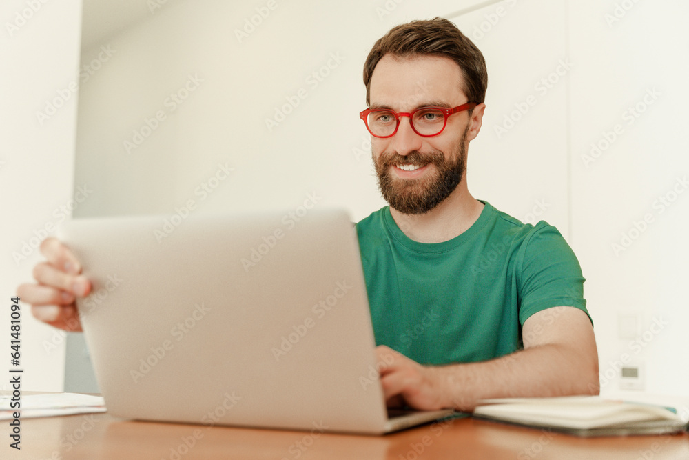 Portrait of positive IT specialist sitting at desk using laptop, working online at workplace Portrait of positive IT specialist sitting at desk using laptop, working online at workplace