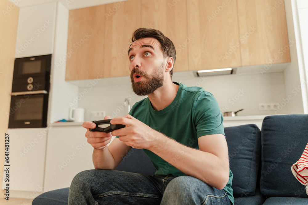 Portrait of excited handsome bearded male gamer playing video game, holding joystick Portrait of excited handsome bearded male gamer playing video game, holding joystick
