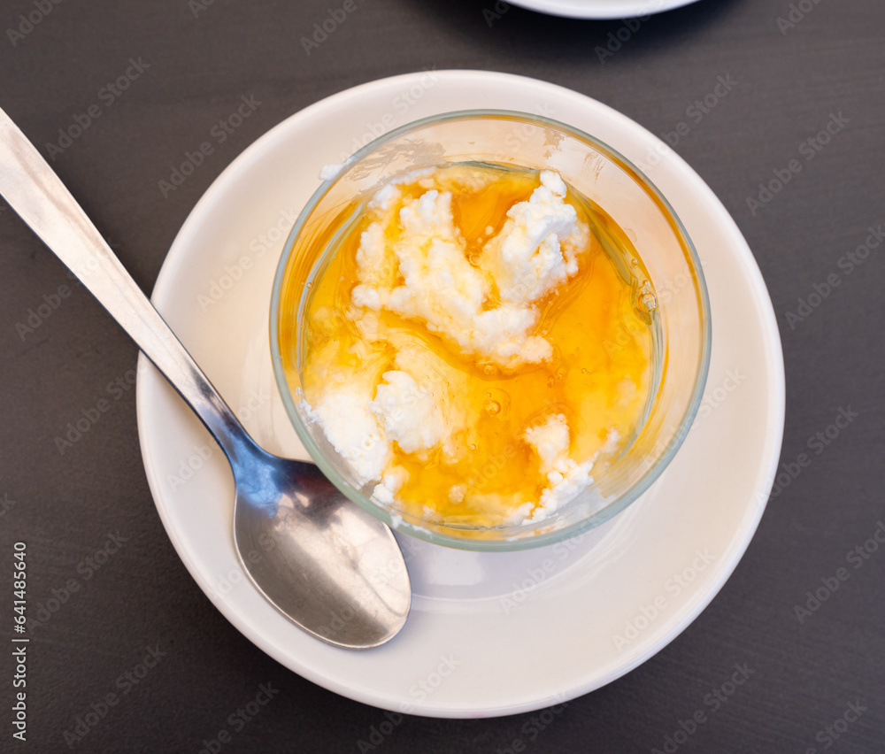 Sweet dessert of curd cheese and honey served with teaspoon on the table
