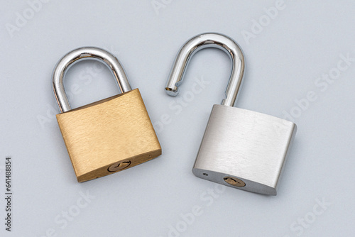 Locked golden and unlocked silver padlock on the gray background.