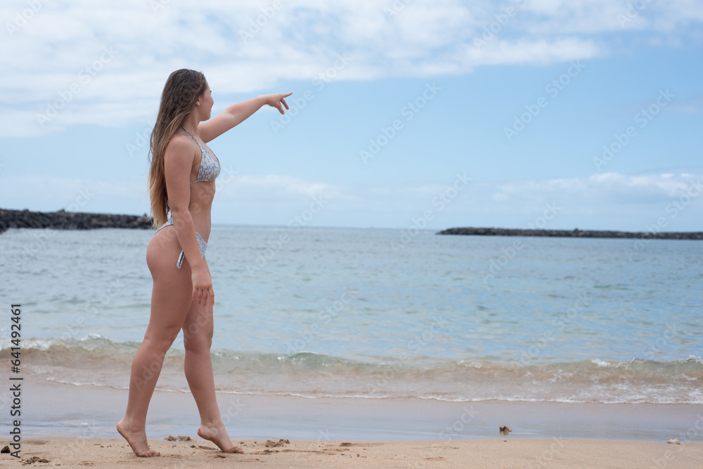 A beautiful tall long-legged girl in a swimsuit walks along the sandy shore of the sea of Georgia