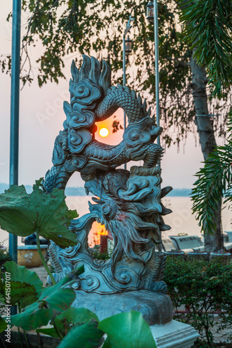 Sun shining through a Buddhist dragon statue,at sunset,Am Sopse Temple,Pakse,Laos. photo