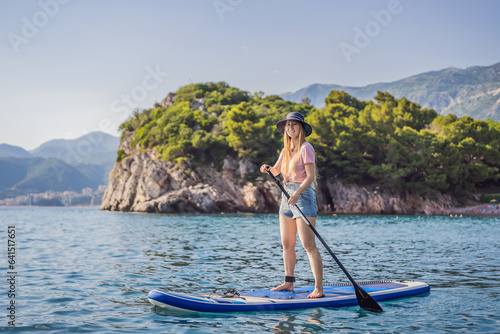 Young women Having Fun Stand Up Paddling in blue water sea near st stefan island against the backdrop of Milocer Park in Montenegro. SUP © galitskaya