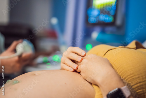 In the Hospital  Close-up Shot of the Doctor does Ultrasound Sonogram Procedure to a Pregnant Woman. Obstetrician Moving Transducer on the Belly of the Future Mother