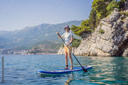 Young men Having Fun Stand Up Paddling in blue water sea near st stefan island against the backdrop of Milocer Park in Montenegro. SUP © galitskaya
