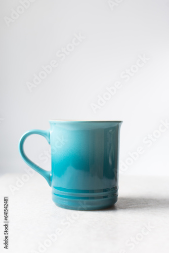 Ombre blue ceramic mug with white background and copy space, handmade gradient blue ceramic coffee cup on a white table
