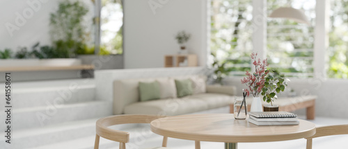 Close-up image of a wooden table with a wooden chair in a modern spacious bright living room.