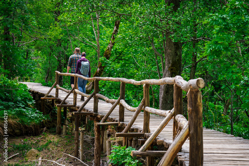 Tourists walk in the park on a wooden deck in the green forest near the lake. Plitvice Lake, Croatia, Central Europe, travel and nature concept © Ilja