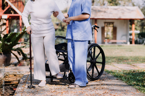 Asian young woman nurse at nursing home take care disabled senior man. Caregiver doctor serve physical therapy for older elderly patient to exercise and practice walking on walker or cane at backyard.