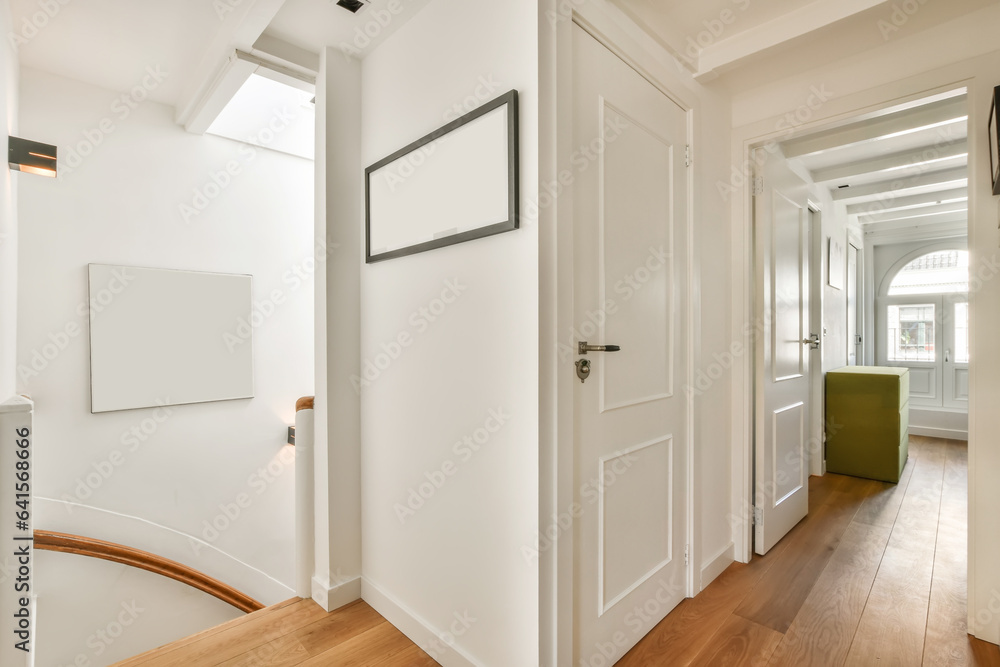 Fototapeta premium a hallway with white walls and wood flooring the room is well lit by natural light from the skylight