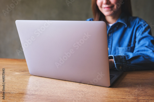 Closeup image of a woman working on laptop computer on wooden table