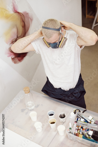 Man in respirator standing at table with paints photo