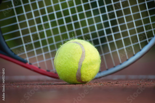 Yellow tennis ball and racquet on hard court surface