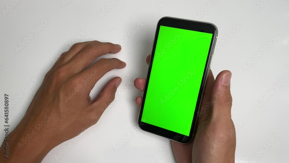 Male hand hold phone, scroll, swipe, tap on phone green screen chroma key point of view shot on white table with hands gesture beats fist on the table. Aggression and frustration concept Male hand hold phone, scroll, swipe, tap on phone green screen chroma key point of view shot on white table with hands gesture beats fist on the table. Aggression and frustration concept