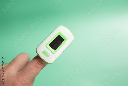 Pulse oximeter on finger showing oxygen saturation and heart rate. 