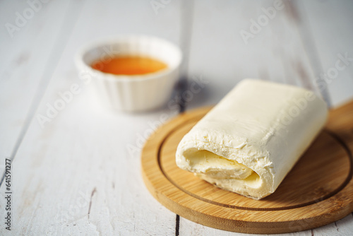 Close up picture of white cream milky kaymak butter roll poured with honey on wooden plate. photo