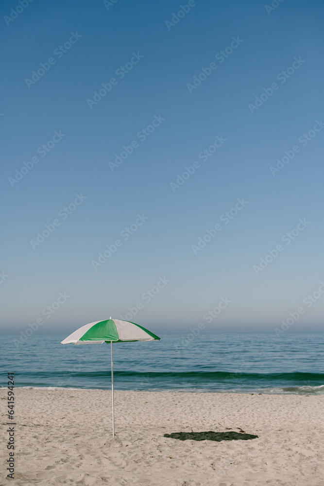 White and green umbrella on empty Carlsbad California beach