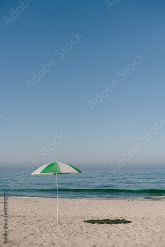 White and green umbrella on empty Carlsbad California beach