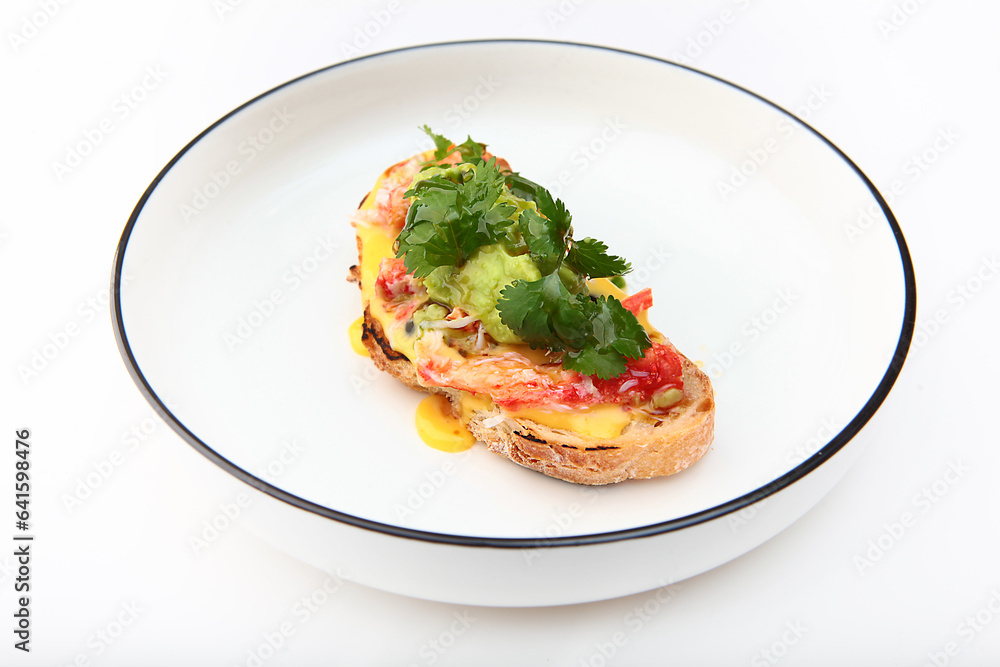 Spanish tapas is traditional sandwich snack for wine or beer - crab meat on piece of bread with tomatoes and avocado puree. Delicious crab dish. Crab bruschetta.Copy space. Isolated object. Spanish tapas is traditional sandwich snack for wine or beer - crab meat on piece of bread with tomatoes and avocado puree. Delicious crab dish. Crab bruschetta.Copy space. Isolated object.