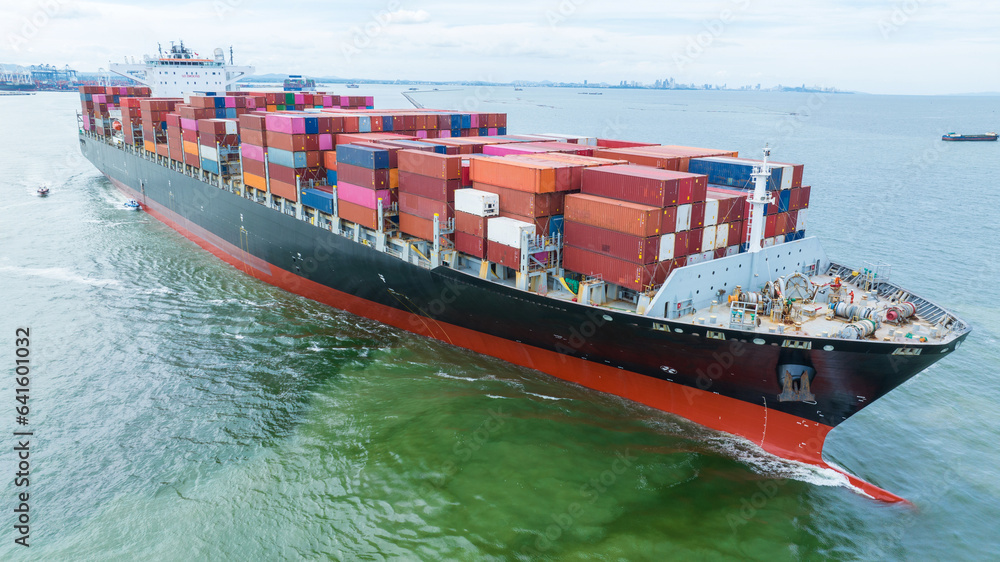 Fototapeta premium Aerial side view of cargo container ship carrying container from custom container depot go to ocean concept freight shipping by ship service on blue sky .Freight Forwarding Service