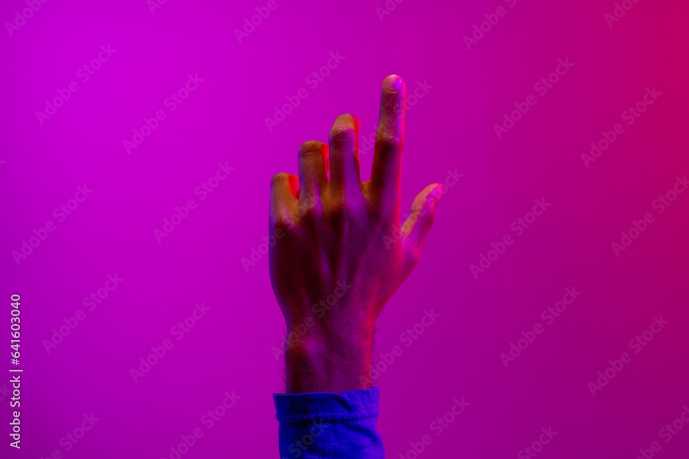 Hand of caucasian businessman pointing with copy space on neon pink to purple background Hand of caucasian businessman pointing with copy space on neon pink to purple background