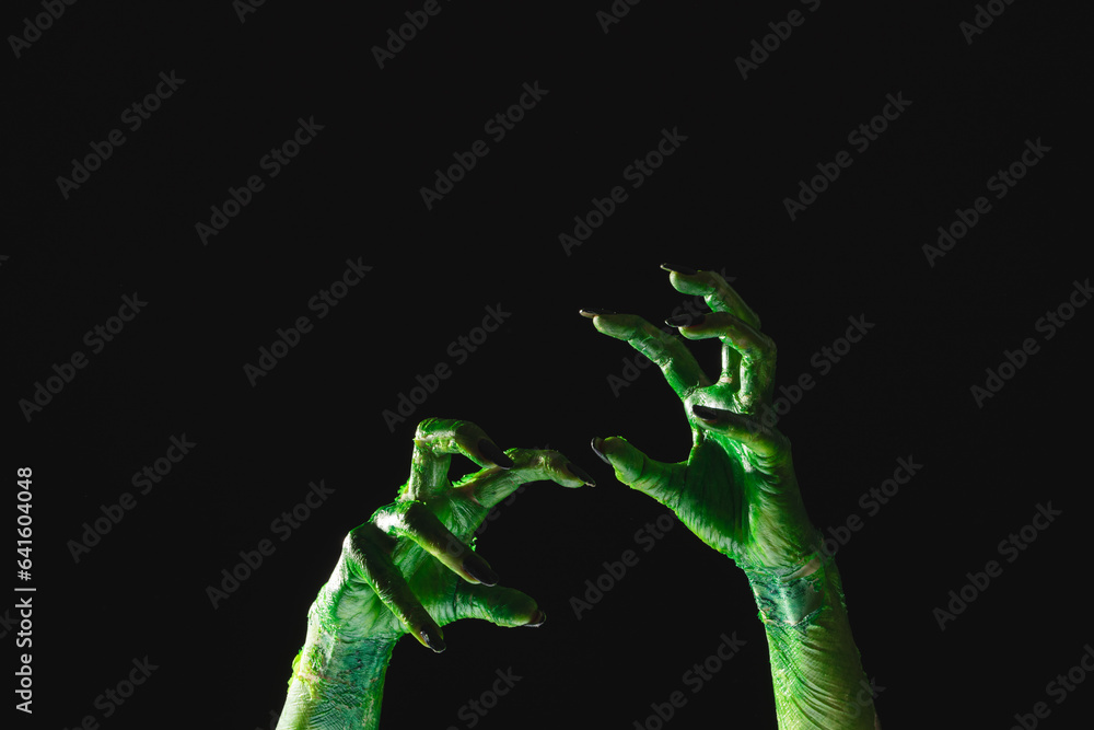 Green monster hands with black nails reaching on black background Stock