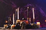 Pumpkins, skulls and burning candles on purple background