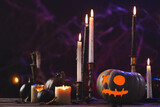 Carved pumpkins and burning candles on purple background