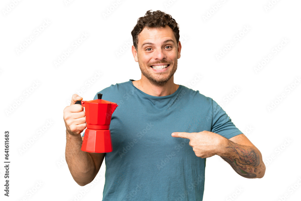 Brazilian man holding coffee pot over isolated chroma key background with surprise facial expression Brazilian man holding coffee pot over isolated chroma key background with surprise facial expression